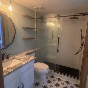 Bathroom remodel with star-patterned tile floor and glass shower