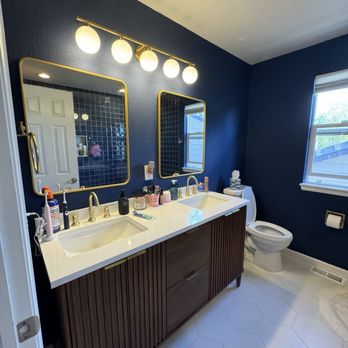 Dual vanity remodel with brass fixtures and navy walls