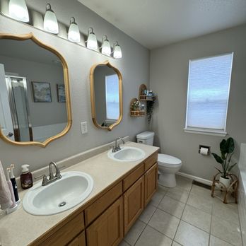 Dual vanity bathroom remodel with brass mirrors