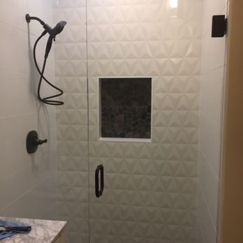 Modern walk-in shower with patterned tile wall and black fixtures