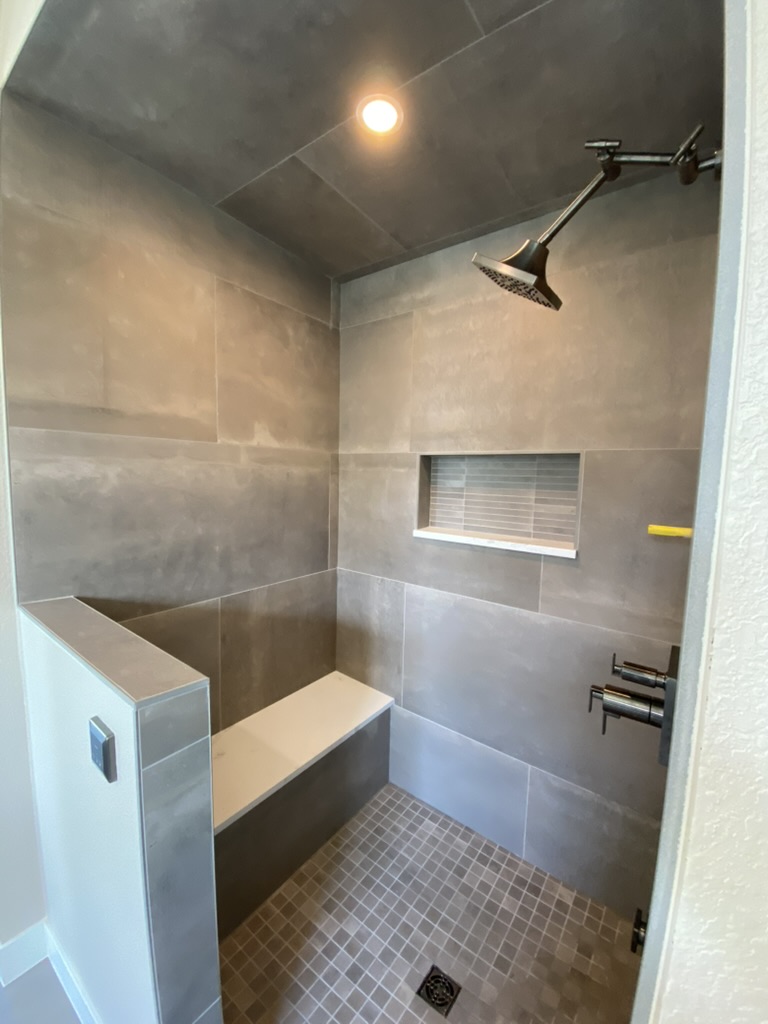Custom steam shower with a built-in bench, recessed niche, and tiled ceiling